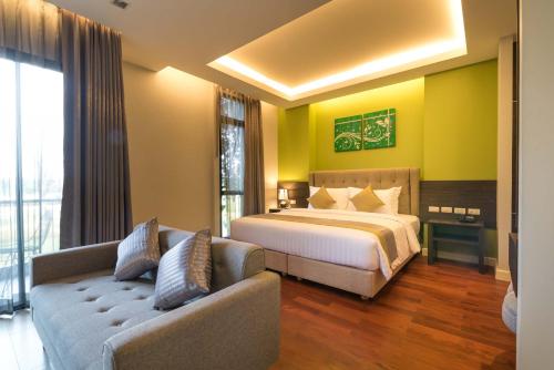 a hotel room with a bed and a couch at Green Ville Laguna Hotel in Sung Noen