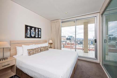een slaapkamer met een groot bed en een groot raam bij Embassy Apartment North Terrace in Adelaide