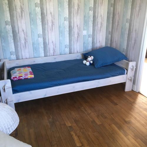 un lit blanc avec un ours en peluche assis sur lui dans l'établissement Ma maison, à Créhen