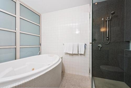 een witte badkamer met een bad en een douche bij Embassy Apartment North Terrace in Adelaide