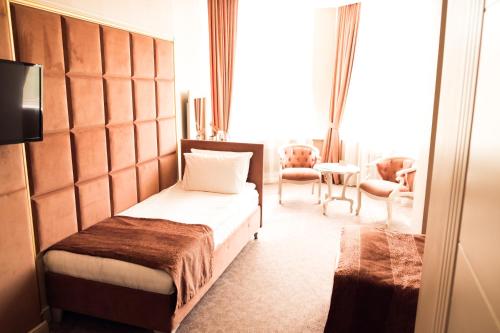 a bedroom with a bed and a table and chairs at Grand Sapphire Hotel in Almaty