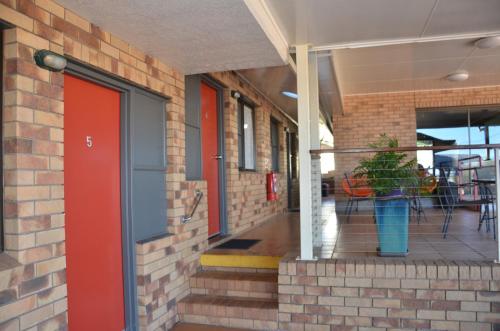 a brick building with a red door and a potted plant at Sunray Motor Inn in Toowoomba