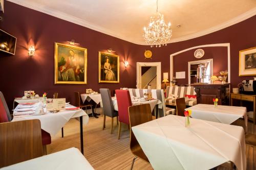 a restaurant with white tables and chairs and a chandelier at Arosfa Hotel London by Compass Hospitality in London