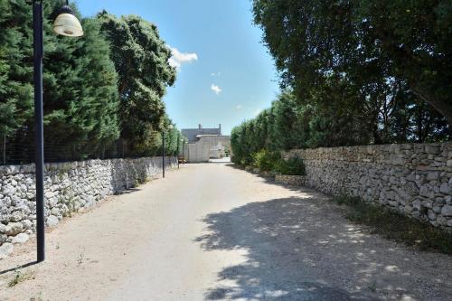 マーリエにあるMasseria i Cocciの石壁と街灯の未舗装道路