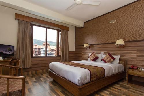 a hotel room with a bed and a window at Hotel Tulsi in Pokhara