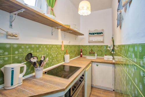 a kitchen with green and white tiles on the wall at The Weekend House - Zsóry in Mezőkövesd