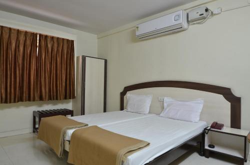 une chambre avec un grand lit avec des draps blancs dans l'établissement Hotel Maya Deluxe, à Hyderabad