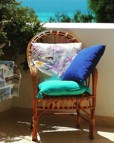 a wicker chair with pillows on a patio at Casa vacanze spiaggia dorata in Marina di Pescoluse