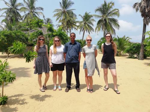 a group of people standing on a beach with palm trees at Dolphin Village in Kalpitiya