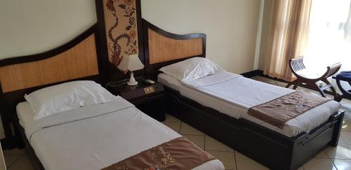 two beds in a hotel room with sidx sidx sidx sidx at Mandalawangi Hotel Syariah in Tasikmalaya