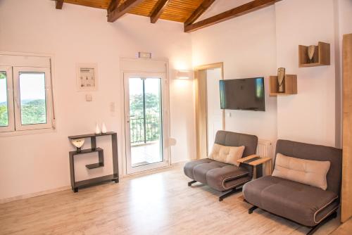 a living room with two chairs and a flat screen tv at Olea Escape Villa in an Olive Estate in Gythio