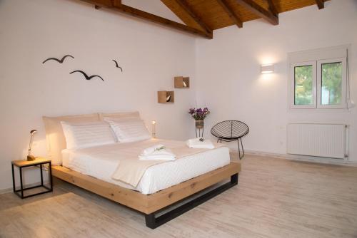 a white bedroom with a large bed with birds on the wall at Olea Escape Villa in an Olive Estate in Gythio