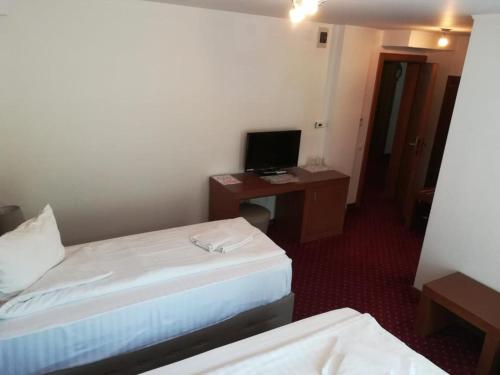 um quarto de hotel com duas camas e uma secretária com um computador em Hotel Dennis em Mediaş