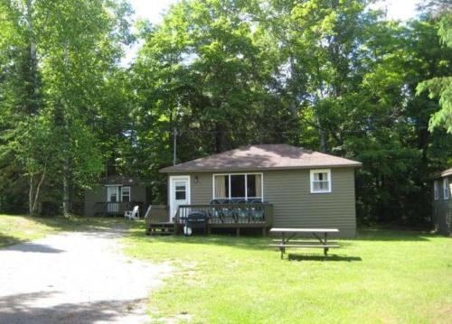 a small house with a picnic table in the yard at Cloverleaf Cottages in Oxtongue Lake