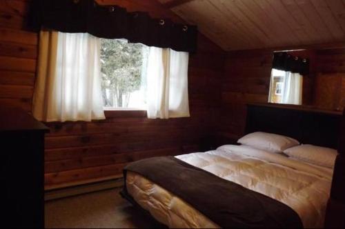 a bedroom with a bed and a window at Cloverleaf Cottages in Oxtongue Lake