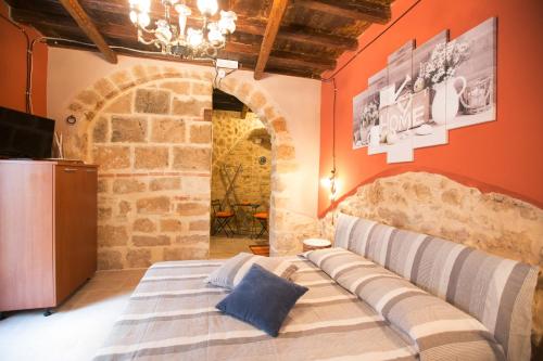 Bett in einem Zimmer mit einer Steinmauer in der Unterkunft Il palazzetto del pescatore in Augusta