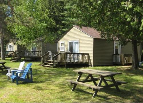 a picnic table and chairs in a yard with a house at Cloverleaf Cottages in Oxtongue Lake