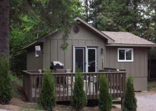 a small house with a porch and a deck at Cloverleaf Cottages in Oxtongue Lake