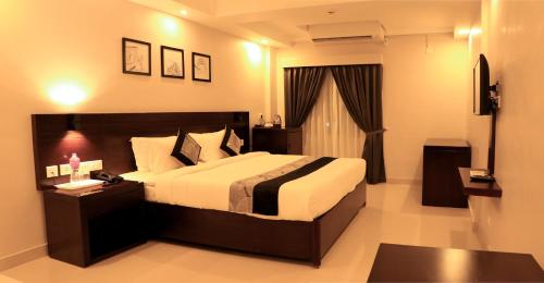 a bedroom with a large bed and a television at D Fort Hotel Kollam in Kollam