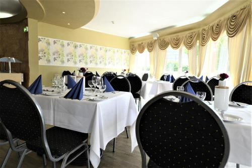 une salle à manger avec des tables et des chaises blanches avec des serviettes bleues dans l'établissement Hotel Best one, à Roßdorf