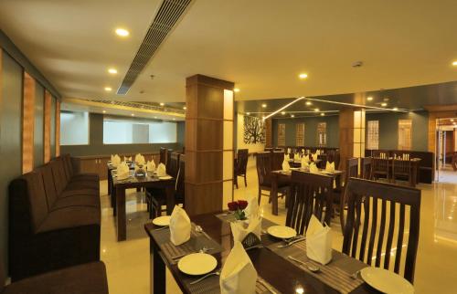 a dining room with tables and chairs in a restaurant at D Fort Hotel Kollam in Kollam