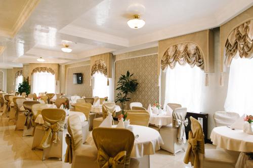 a restaurant with white tables and chairs and windows at Svityaz Resort in Truskavets