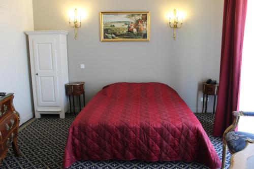 a bedroom with a red bed and a painting on the wall at Hôtel Fleur de Lys Hazebrouck in Hazebrouck