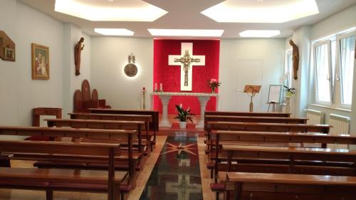 a church with wooden pews and a cross on the wall at Casa Ospitalità San Giuseppe in LʼAquila