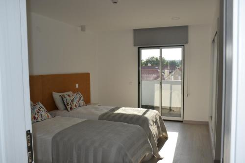 a bedroom with two beds and a large window at Varandas do Mosteiro in Batalha