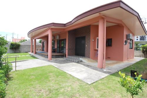 a small house with pink pillars in a yard at Resort Villa The ReLa Inn in Onna