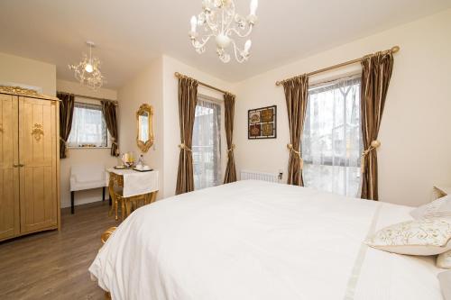 1 dormitorio con cama blanca y lámpara de araña en Rowan Park Lodge en Croydon