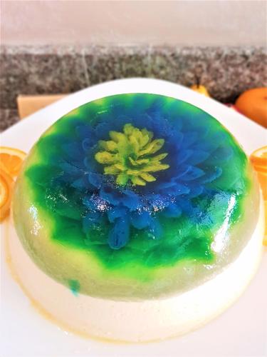 a green and blue cake with a flower on a plate at Grenada Hotel in Sunny Beach