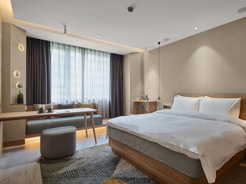 - une chambre d'hôtel avec un lit et un bureau dans l'établissement EBO Hotel Hangzhou Wulin, à Hangzhou