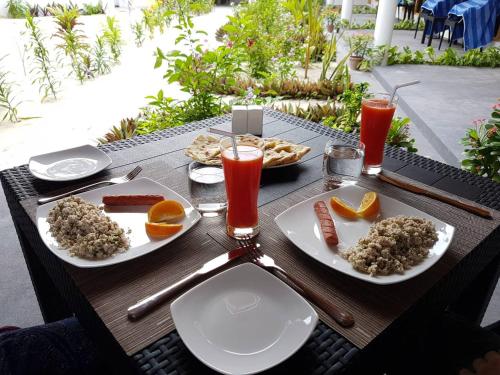 a table with plates of food and drinks on it at Thoddoo Beach Holiday in Thoddoo