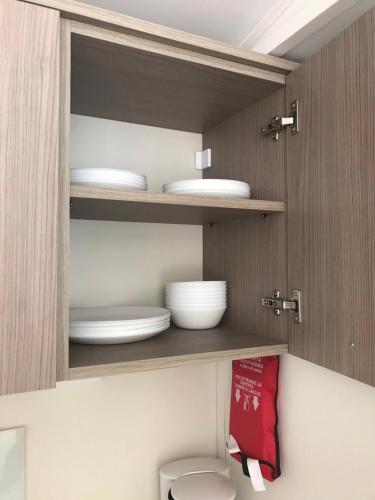 a kitchen with plates and bowls on a shelf at SunVillage Camp- Mobilházak Alsóörsön in Alsóörs