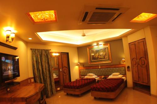 
a hotel room with a large bed and a television at Panchavati Elite Inn in Nashik
