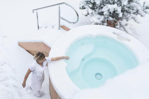a woman standing next to a snow covered bath tub at Hotel Drumlerhof in Campo Tures