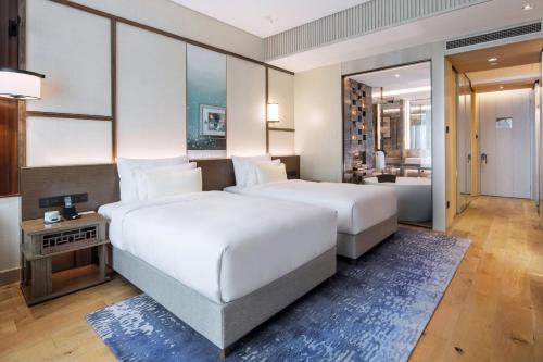 上海市にあるThe Anandi Hotel and SPA - Luxury Healing Hotel for Wellbeingのベッドルーム1室(ベッド2台付)、リビングルームが備わります。