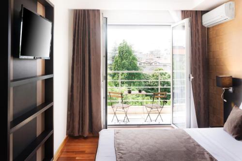 a bedroom with a bed and a sliding glass door with a balcony at Feel Belgrade Apartments in Belgrade