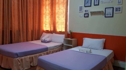 two beds in a small room with a window at Old Orangewood Bed & Breakfast in Baguio
