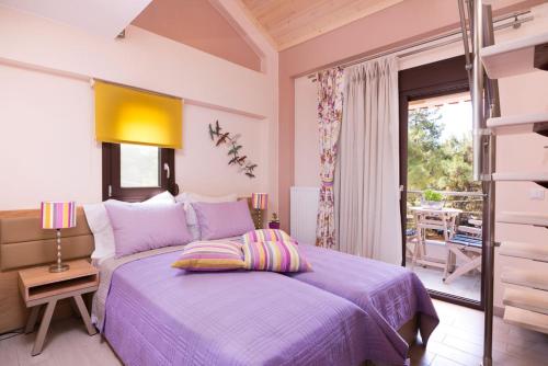 a bedroom with a purple bed and a balcony at Villa Ermioni Apartments in Limenaria