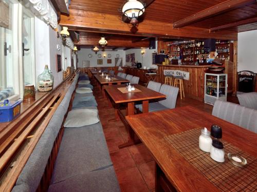 ein Restaurant mit Holztischen und -bänken und einer Bar in der Unterkunft Chata Orlik - all inclusive & wellness in Pec pod Sněžkou