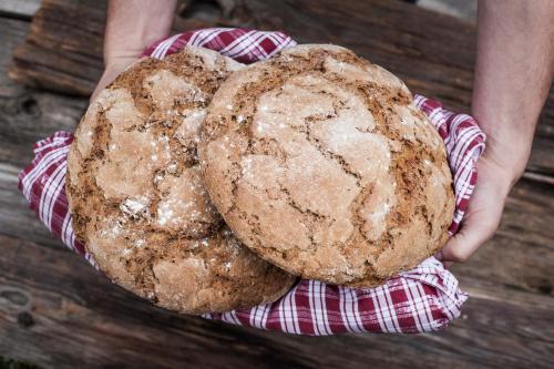 a person holding up two loaves of bread at Hotel Drumlerhof in Campo Tures