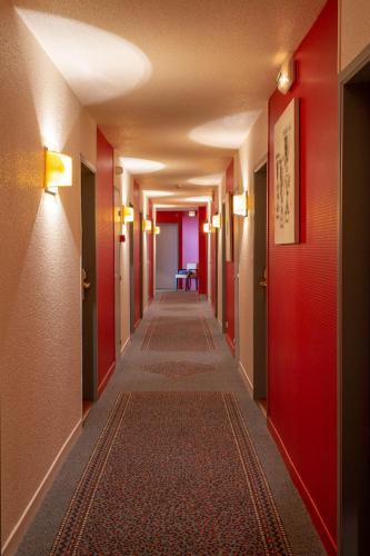 a corridor of a hotel with red walls and a long hallway at Providence Hotel in Vittel