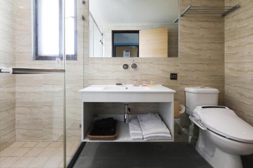 a bathroom with a sink and a toilet and a mirror at KUN Hotel in Taichung