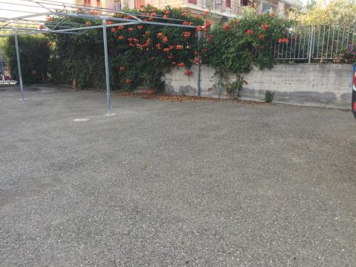 an empty parking lot with red flowers on a fence at Valentina Holiday House in Mascali