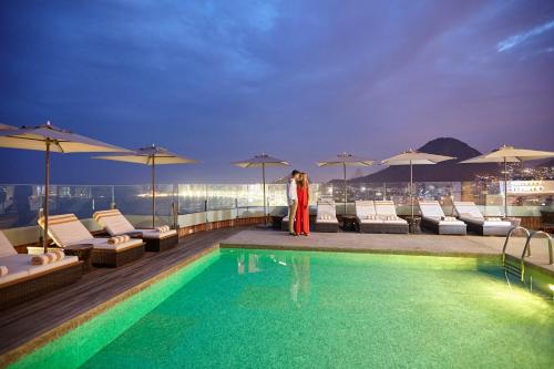 une femme debout à côté d'une piscine dans un bâtiment dans l'établissement PortoBay Rio de Janeiro, à Rio de Janeiro