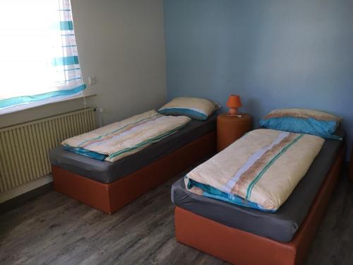two twin beds in a small room with a window at Ferienwohnung Pfeifer in Friedrichsdorf