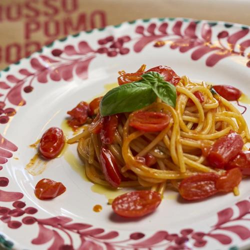 a plate of pasta with tomatoes and basil on it at Hotel Villa Glicini in Pinerolo