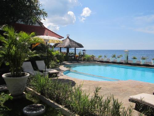 - une piscine avec l'océan en arrière-plan dans l'établissement Kembali Beach Bungalows, à Amed